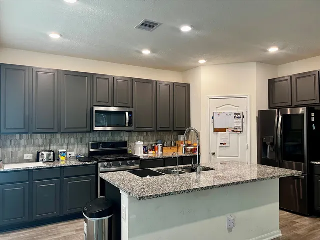 a kitchen with stainless steel appliances granite countertop a refrigerator a sink a stove a microwave a counter space and cabinets