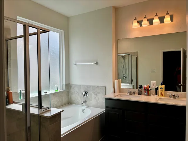 a bathroom with a double vanity sink a mirror and a bathtub