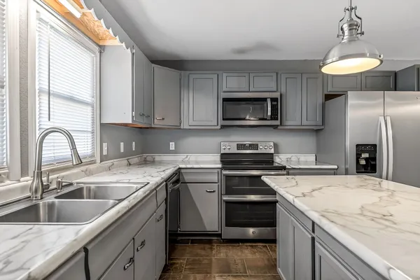 a kitchen with stainless steel appliances granite countertop a sink a stove a refrigerator cabinets and a window