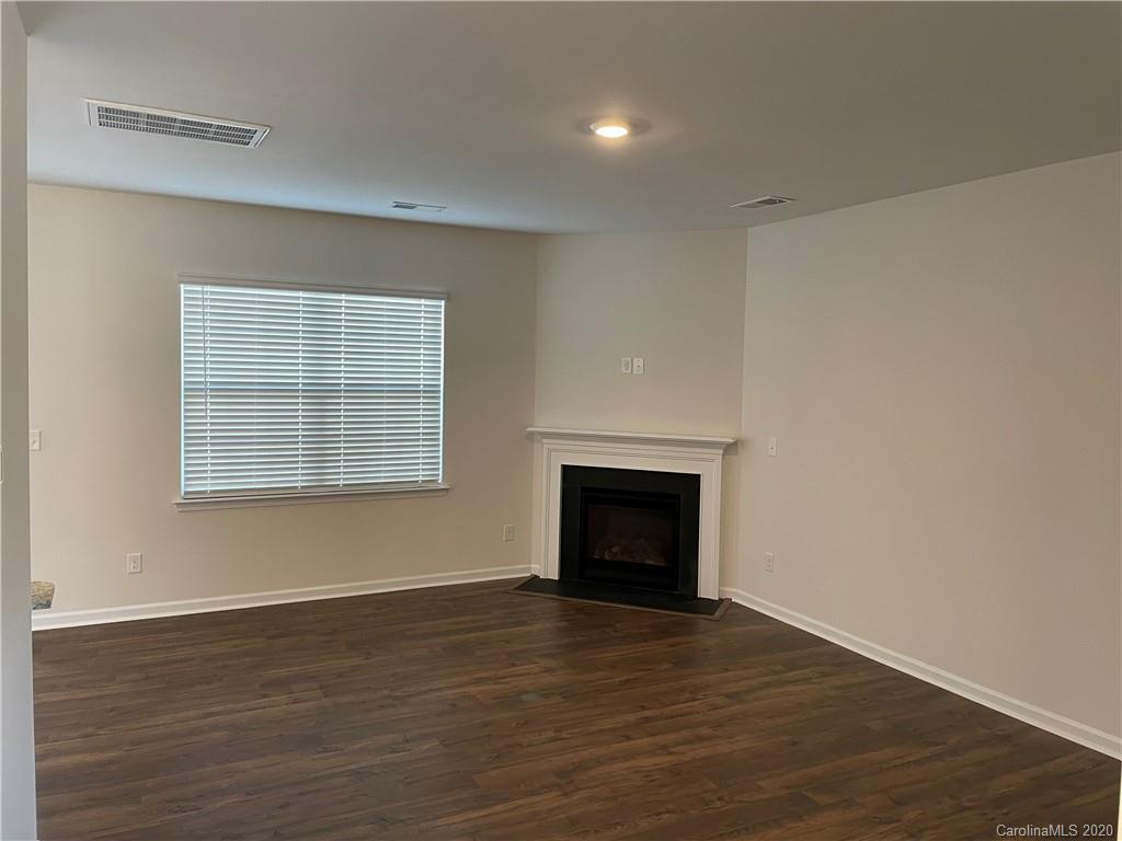 5005 Traynor Road, Unit 18 Charlotte, NC 28216 - Photo 7 of 35 an empty room with wooden floor a fireplace and windows