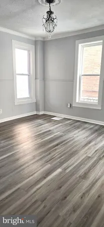 an empty room with wooden floor chandelier and windows