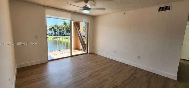 an empty room with wooden floor fan and a floor to ceiling window