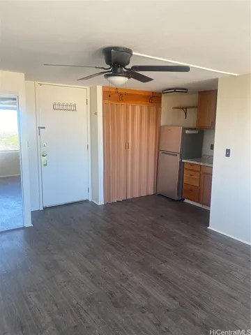 a view of empty room with wooden floor and fan