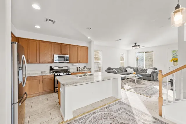 a large white kitchen with stainless steel appliances granite countertop a stove and a sink