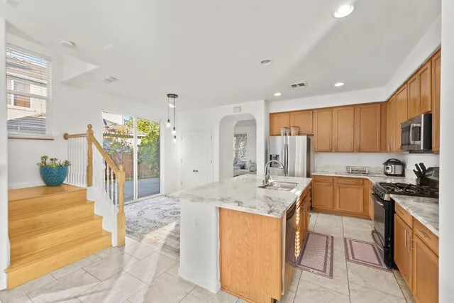 a kitchen with stainless steel appliances granite countertop a refrigerator a stove and a sink