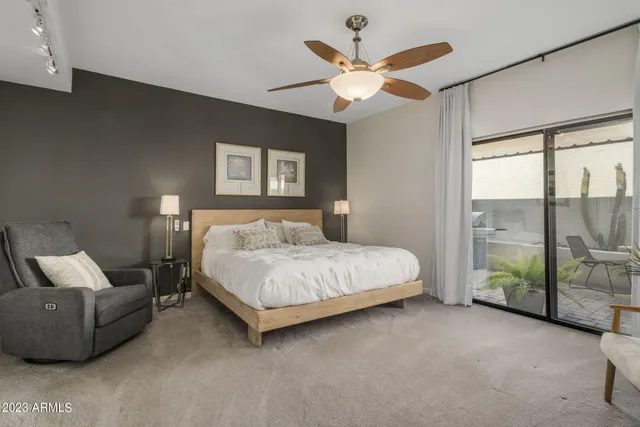 a spacious bedroom with a bed painting on wall and a large window