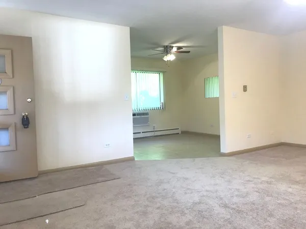 an empty room with windows and fan
