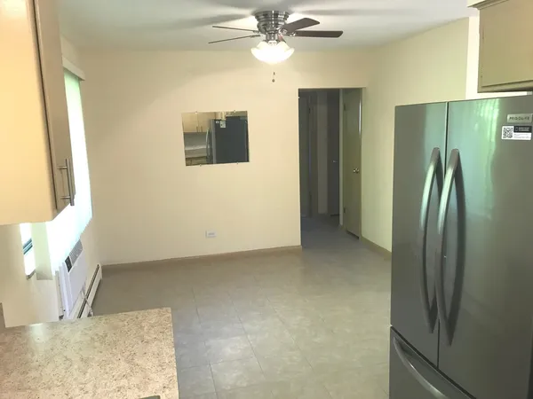 a view of an empty room with window and a kitchen view