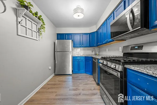 a kitchen with stainless steel appliances granite countertop a refrigerator a stove and a wooden floors