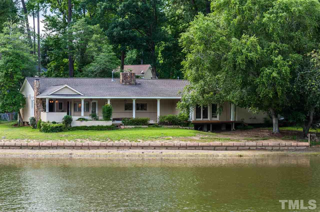 a front view of a house with a yard swimming pool and a large tree