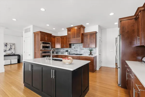 a kitchen with stainless steel appliances granite countertop a sink a refrigerator and wooden cabinets