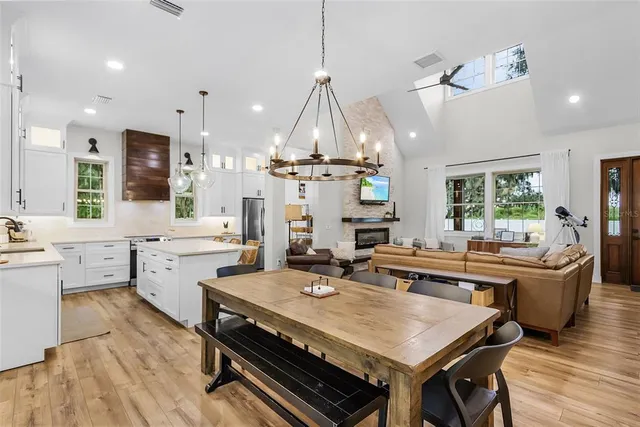 a large white kitchen with a stove a sink a kitchen island with stainless steel appliances a refrigerator a sink and a stove