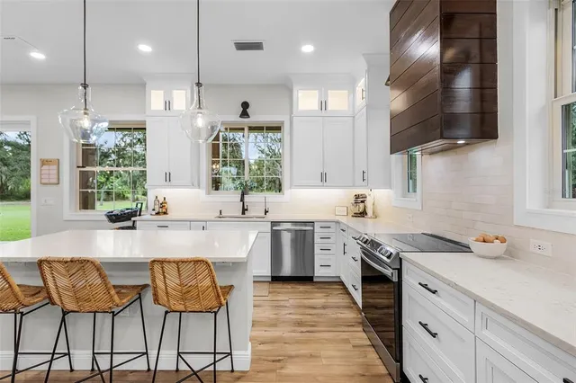 a large white kitchen with a sink a counter and stainless steel appliances