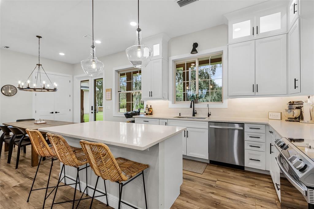 11720 Darsey Road Parrish, FL 34219 - Photo 18 of 60 a large kitchen with cabinets a sink dishwasher a stove and a dining table with wooden floor