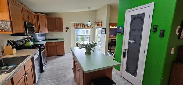 a kitchen with kitchen island stainless steel appliances a table chairs refrigerator and sink