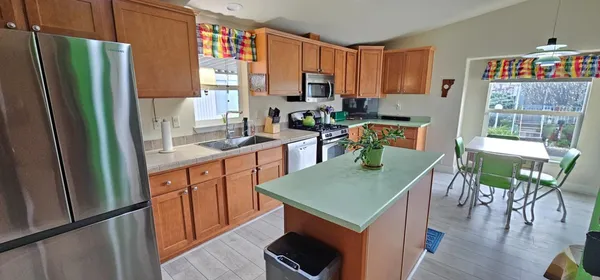 a kitchen with stainless steel appliances granite countertop a refrigerator a stove top oven a sink dishwasher and wooden cabinets with wooden floor