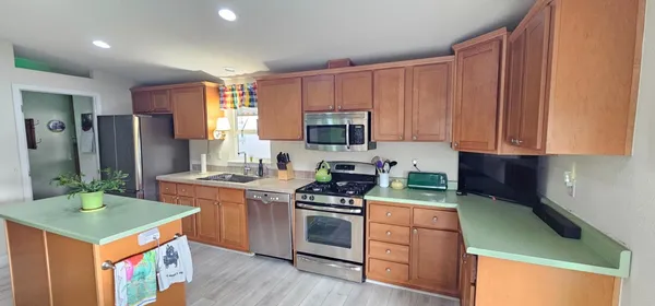 a kitchen with stainless steel appliances granite countertop a stove a sink and a microwave