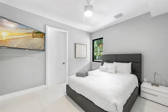 a bedroom with a bed painting on the wall and a large window