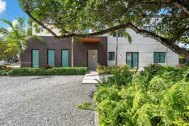 a view of a white house with a large tree space