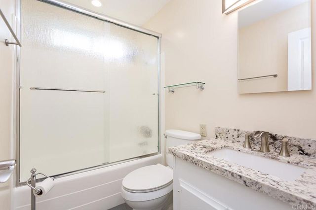 a bathroom with a granite countertop sink toilet and shower