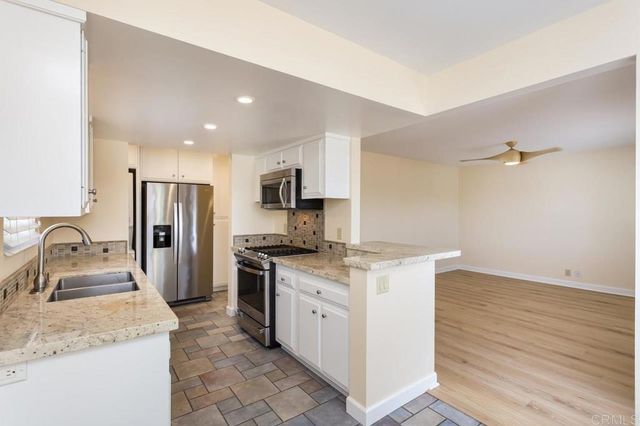 a kitchen with stainless steel appliances granite countertop a sink stove refrigerator and cabinets