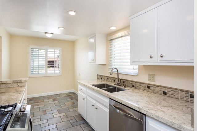 a kitchen that has a sink a window and cabinets