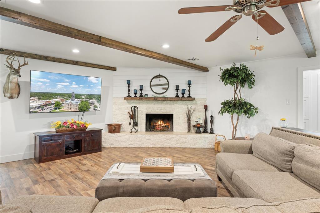 Living room features exposed beams and wood burning fireplace