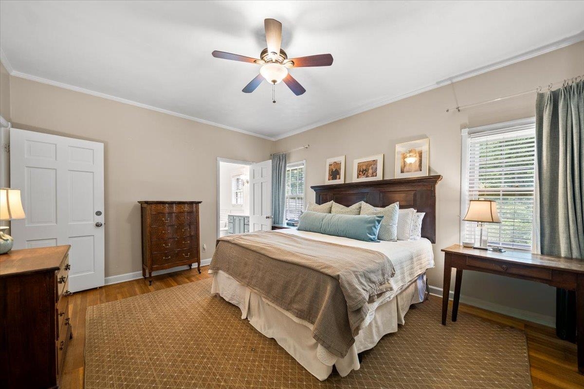 1273 Brookfield Road Memphis, TN 38119 - Photo 22 of 40 Spacious primary bedroom featuring wood-finish flooring, a ceiling fan with integrated lighting, and multiple windows providing natural light