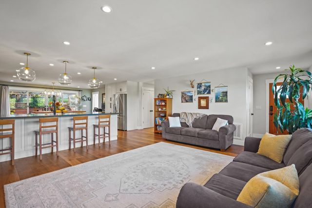 a living room with furniture and a dining table with wooden floor