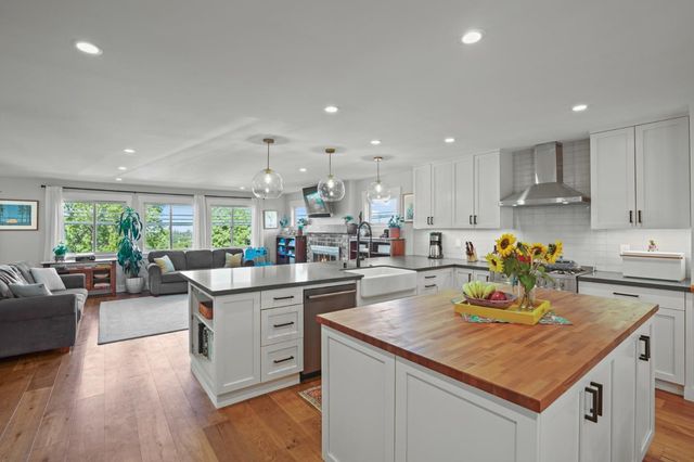 a kitchen with a stove a sink dishwasher a refrigerator and white cabinets with wooden floor