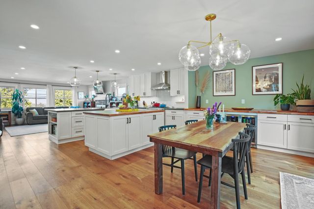 a kitchen with stainless steel appliances kitchen island granite countertop a table chairs and a refrigerator