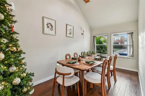 a kitchen with stainless steel appliances granite countertop a refrigerator a sink dishwasher a stove a dining table and chairs with wooden floor