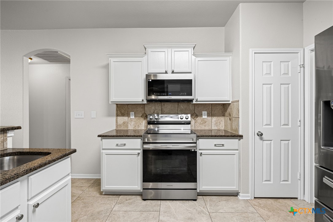 4712 Ramhorn Killeen, TX 76542 - Photo 12 of 27 a kitchen with granite countertop white cabinets and stainless steel appliances