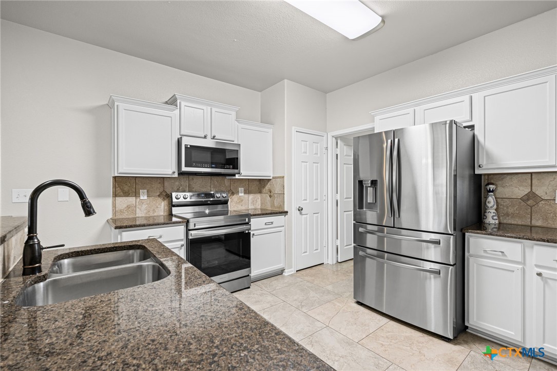 4712 Ramhorn Killeen, TX 76542 - Photo 13 of 27 a kitchen with granite countertop a refrigerator stove and microwave