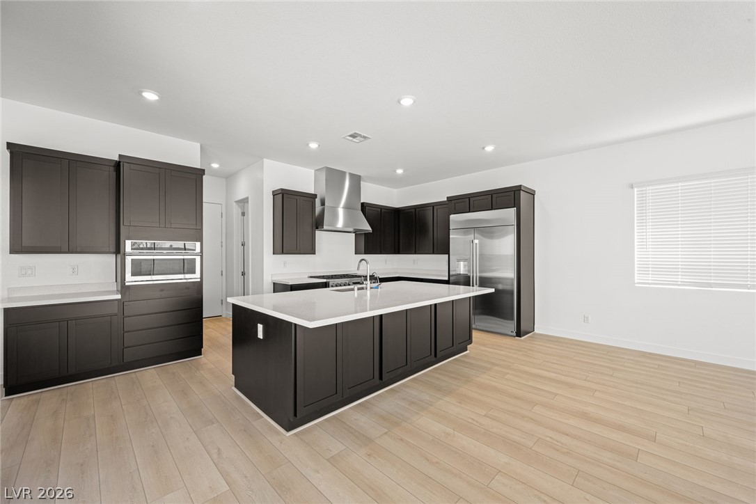 9983 Decano Ridge Street Las Vegas, NV 89141 - Photo 14 of 39 A contemporary kitchen features dark cabinetry, light countertops, and gleaming stainless steel appliances.