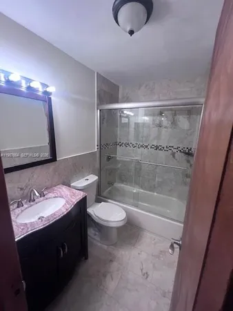 a bathroom with a granite countertop sink a toilet and shower