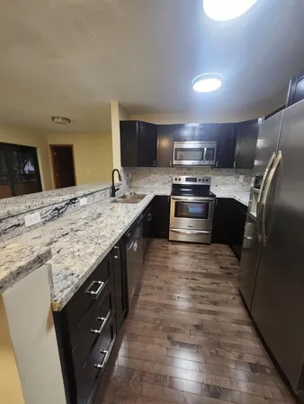 a large kitchen with granite countertop a stove top oven and sink