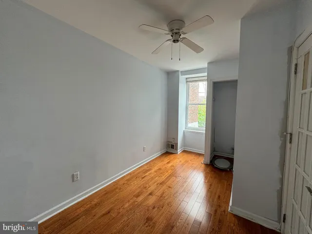 a view of empty room with wooden floor and fan