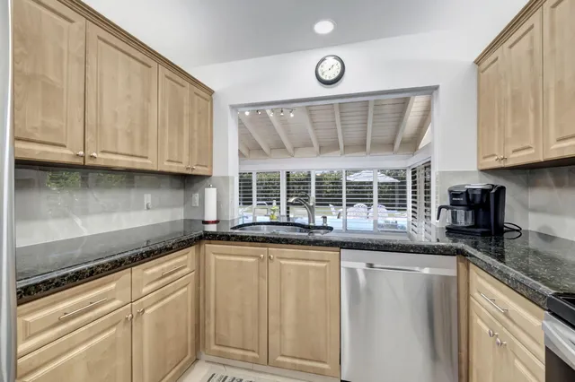 a kitchen with stainless steel appliances granite countertop a sink and cabinets with wooden floor