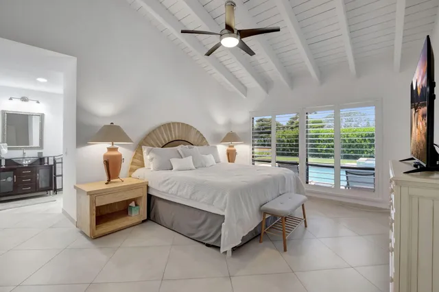 a spacious bedroom with a bed a large window and flat screen tv