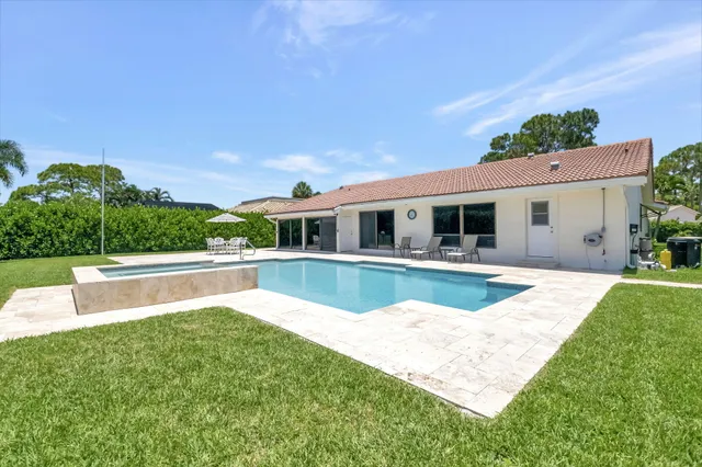 a view of house with swimming pool and a yard