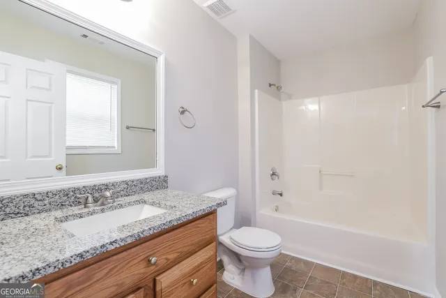 a bathroom with a granite countertop sink a toilet and shower