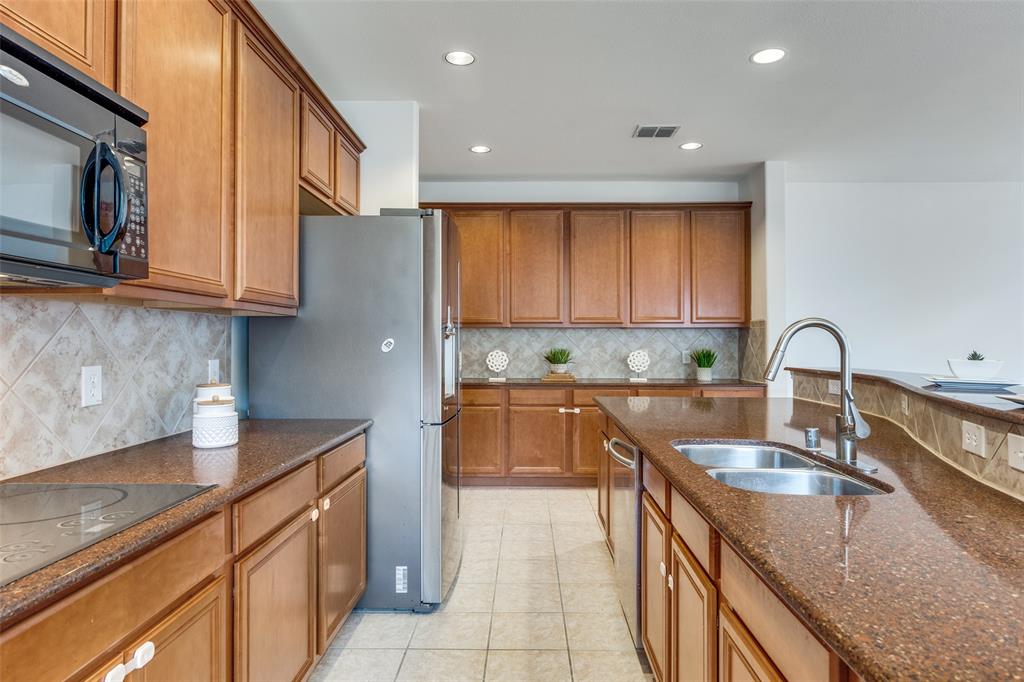 2025 Testament Trail Plano, TX 75074 - Photo 9 of 29 a kitchen with kitchen island granite countertop a sink stainless steel appliances and cabinets