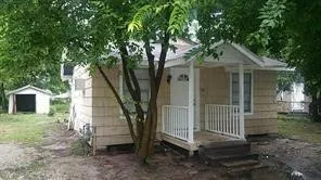 a view of a small house with a yard and large tree