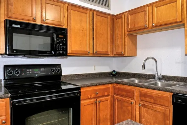 a kitchen with granite countertop stainless steel appliances a stove a sink a microwave and cabinets