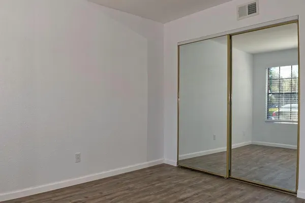a view of an empty room with wooden floor and closet