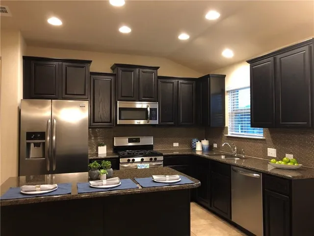 a kitchen with stainless steel appliances granite countertop a sink refrigerator and microwave