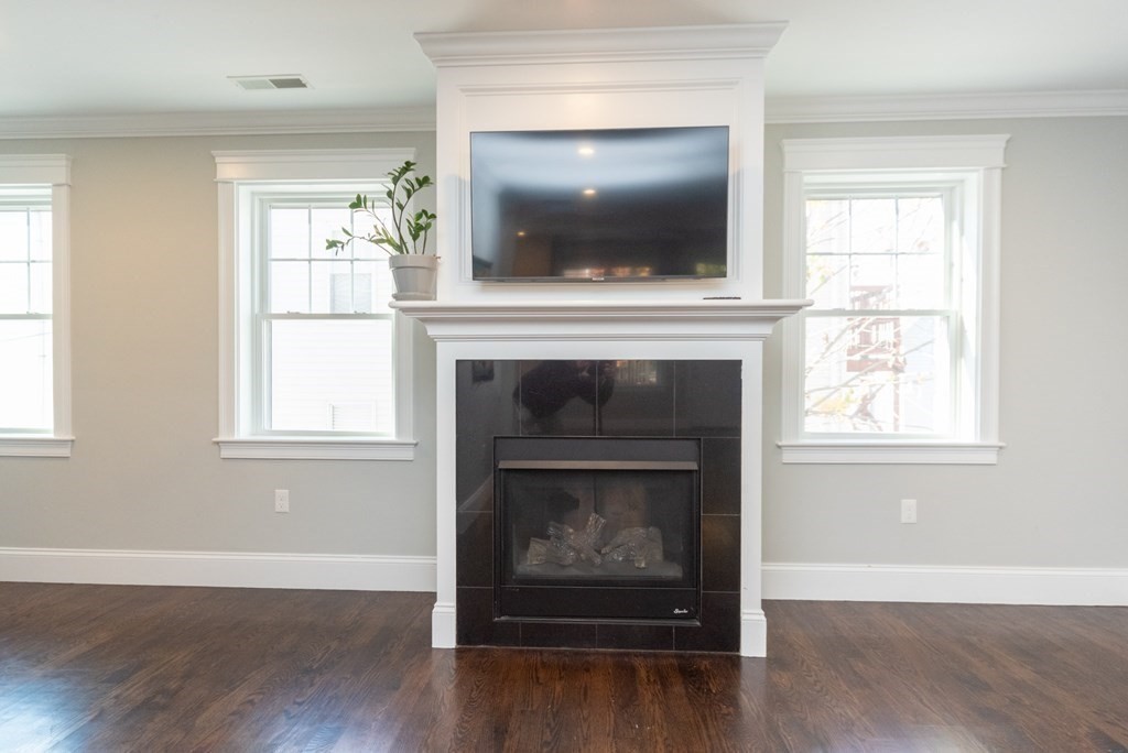 156 Ash Street, Unit 2 Waltham, MA 02453 - Photo 13 of 39 a living room with a fireplace and a flat screen tv