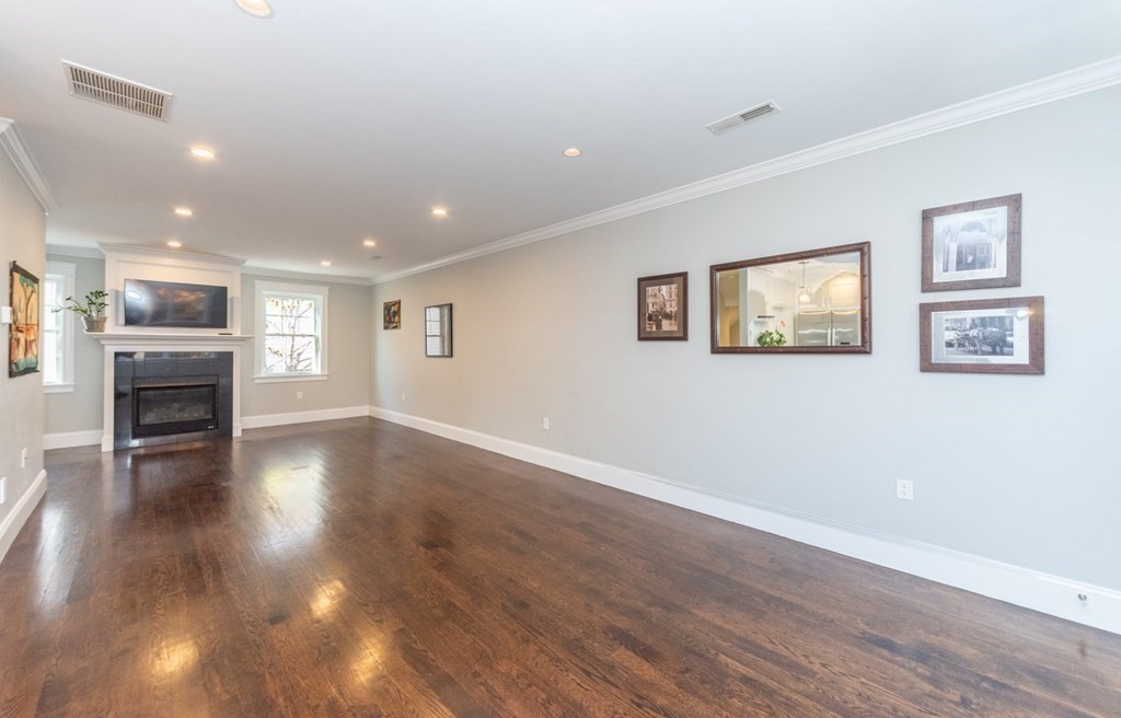 156 Ash Street, Unit 2 Waltham, MA 02453 - Photo 14 of 39 a view of empty room with wooden floor and fireplace