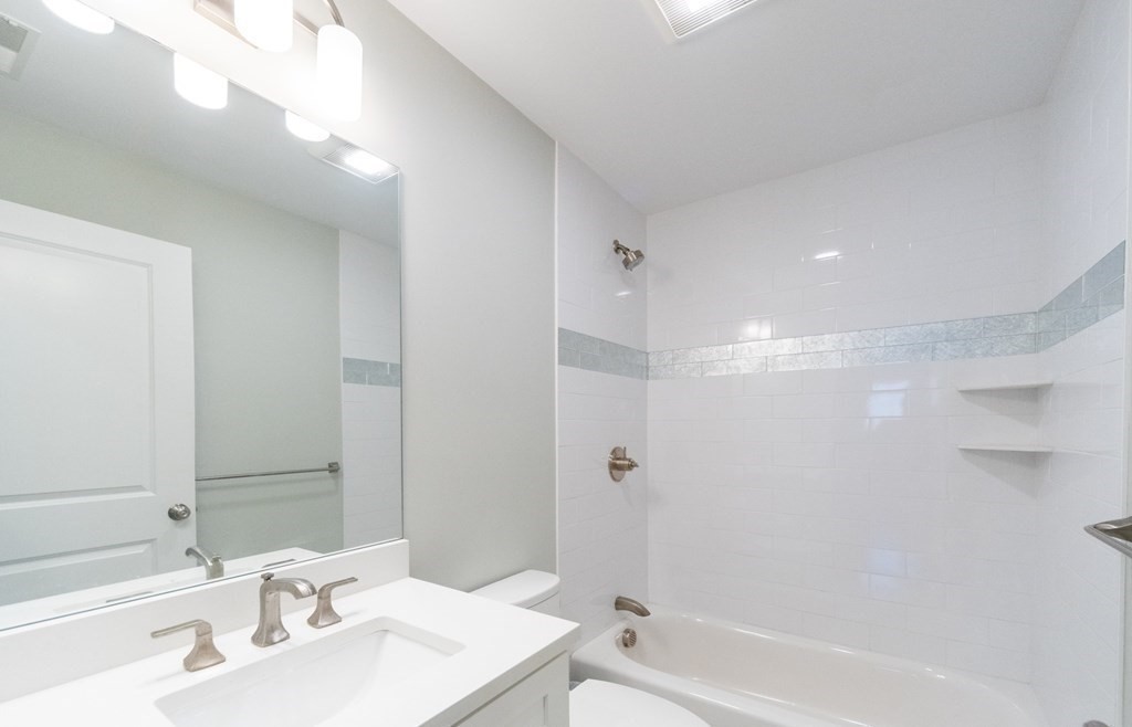 156 Ash Street, Unit 2 Waltham, MA 02453 - Photo 32 of 39 a bathroom with a bathtub shower sink vanity and a mirror